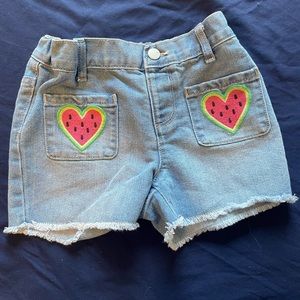 Light wash girls jean shorts. With watermelon heart designs on pockets